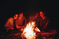 Group of friends sitting around a bonfire at a campsite