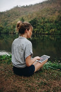 Woman alone in nature using a digital tablet with entertainment application on the screen internet connection and leisure concept