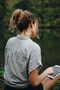 Rear view of woman using digital tablet in a jungle