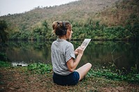 Woman alone in nature listening to music with headphones and digital tablet music and relaxation concept