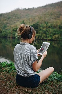 Woman alone in nature listening to music with headphones and digital tablet music and relaxation concept