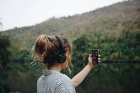 Woman alone in nature listening to music with headphones and smartphone
