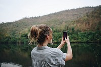 Closeup of a woman hand raising her smartphone up taking a photo of nature travel and tourism concept