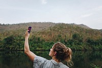 Woman alone in nature raising smartphone above signal problem and smartphone addiction concept