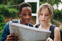 Two women friends looking at a map together travel and teamwork concept