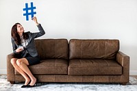 Businesswoman sitting on couch holding icon