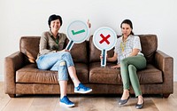 Women sitting on couch holding icons