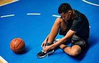 African American teenage boy tying his shoe laces on a basketball court