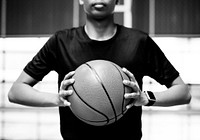 African American teenage boy holding a basketball on the court