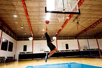 Afrian American teenage boy playing basketball alone on the court