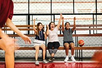 Teenage girls cheering the boys playing basketball