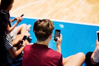 Group of young teenager friends on a basketball court relaxing and using smartphone