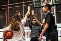 Group of teenager friends on a basketball court giving each other a high five