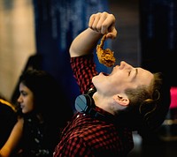 Close up of teenage boy eating fried chicken with his friends