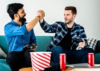 Men playing video game on sofa giving each other a high five leisure and teamwork concept
