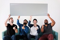 Group of diverse friends sitting on couch holding blank board