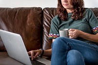Woman using laptop on sofa in the morning