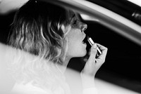 Woman putting on lipstick in a car