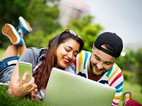 Friends using their mobile devices laying on the grass