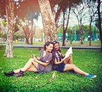 Friends sitting on the grass by the tree