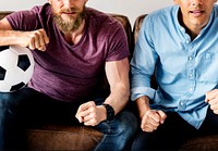 Man sitting together on a couch watching sport