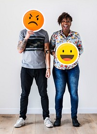 Interracial couple holding an expressive emoticon face facial expression frown and smile relationship issue concept