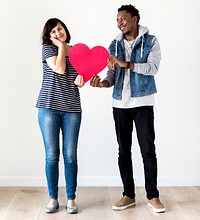 Happy smiling interracial couple holding a red heart
