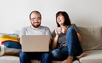 Couple using laptop together on the couch