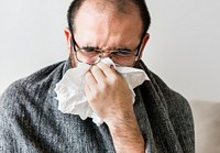 Man sneezing into tissue paper