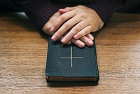 Hands over bible on wooden table