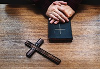 Hands over bible on wooden table