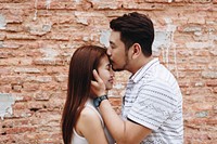 Lovely asian couple by a brick wall