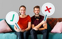 Cheerful couple holding vote icon sitting on a couch