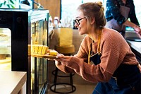 Woman getting cake out of the display fridge