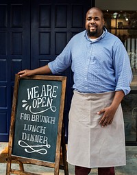 A cheerful business owner standing with open blackboard