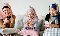 Group of islamic girls sitting on the couch and using smart phones