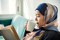 Muslim woman reading and drinking coffee
