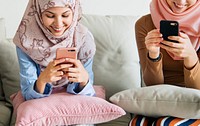 Group of islamic girls sitting on the couch and using smart phones