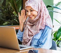 Islamic woman using laptop for video call with happy face