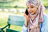 Muslim woman talking on the phone at the park