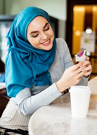 Muslim woman smiling while texting on her phone