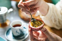 Woman scooping out the insides of a passion fruit