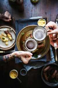 Tattooed couple having sausage and beers for dinner