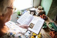 Happy elderly woman reading a cookbook