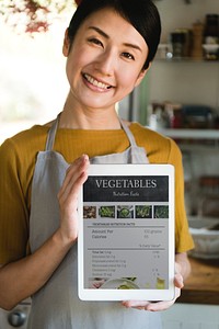 Happy woman holding a tablet with vegetable nutritional facts