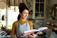 Japanese woman reading a cookbook in the kitchen