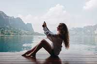 Woman using her phone by a lake
