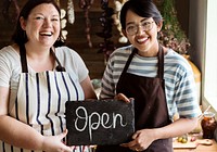 Cheerful deli shop owners showing an open sign