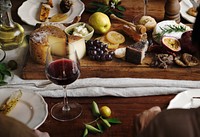 People eating a platter of cheese with seasonal fruits and wine