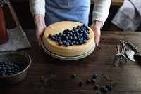 Woman holding a cheesecake topped with blueberries